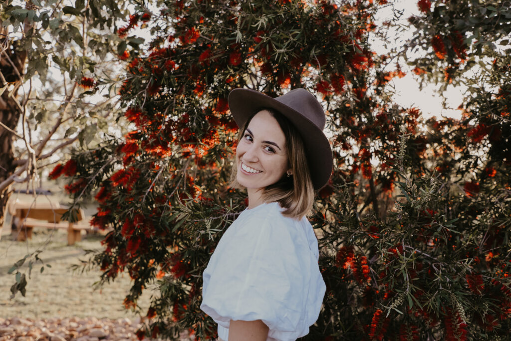 Standing in front of bottle brush bush with an Akubra hat on
